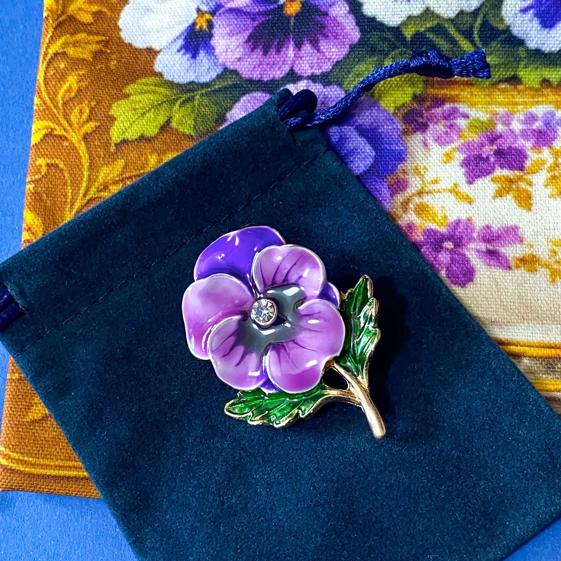 golden floral fabric pouch featuring purple and white pansies in a vintage teacup with matching enamel and metal rhinestone brooch in velvet gift bag and coordinating pansy greeting card with kraft envelope.