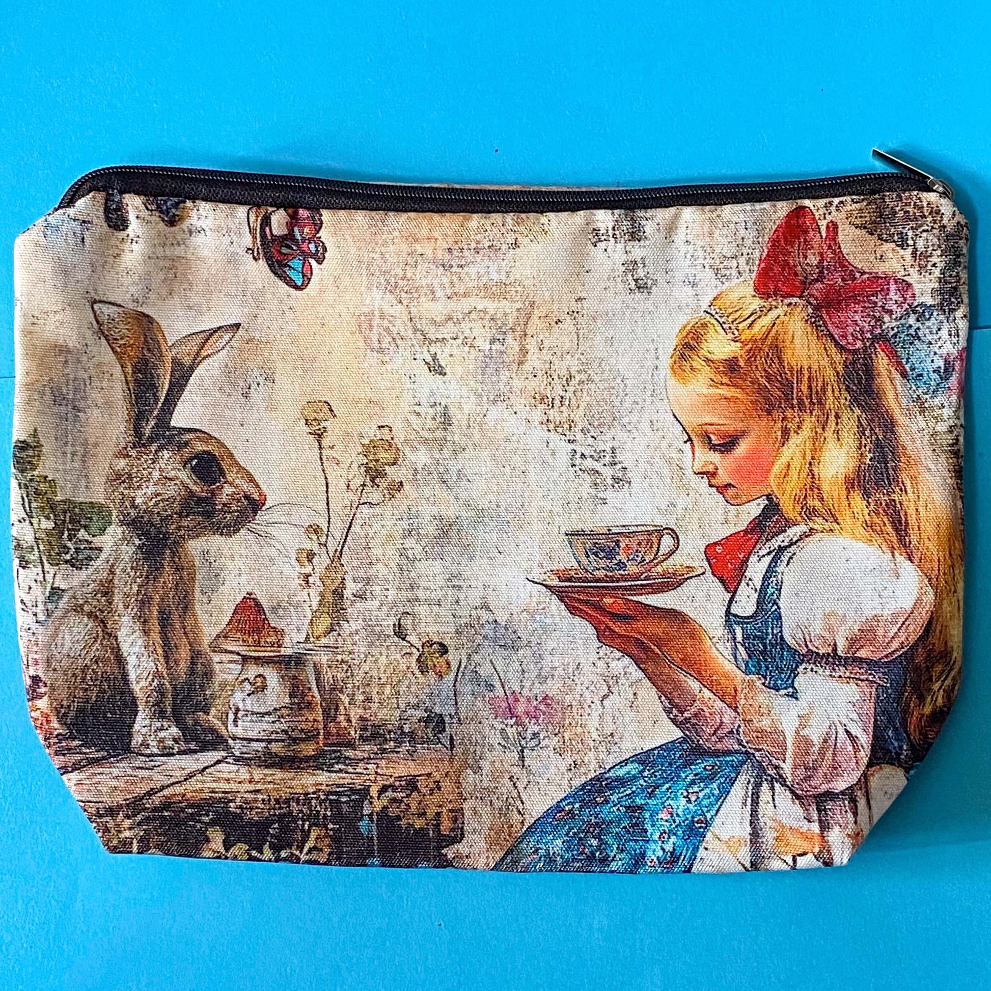 lightweight fabric zip pouch featuring a vintage inspired alice in wonderland scene with a girl enjoying afternoon tea with a rabbit on softly aged storybook background. uk cute gifts shop.