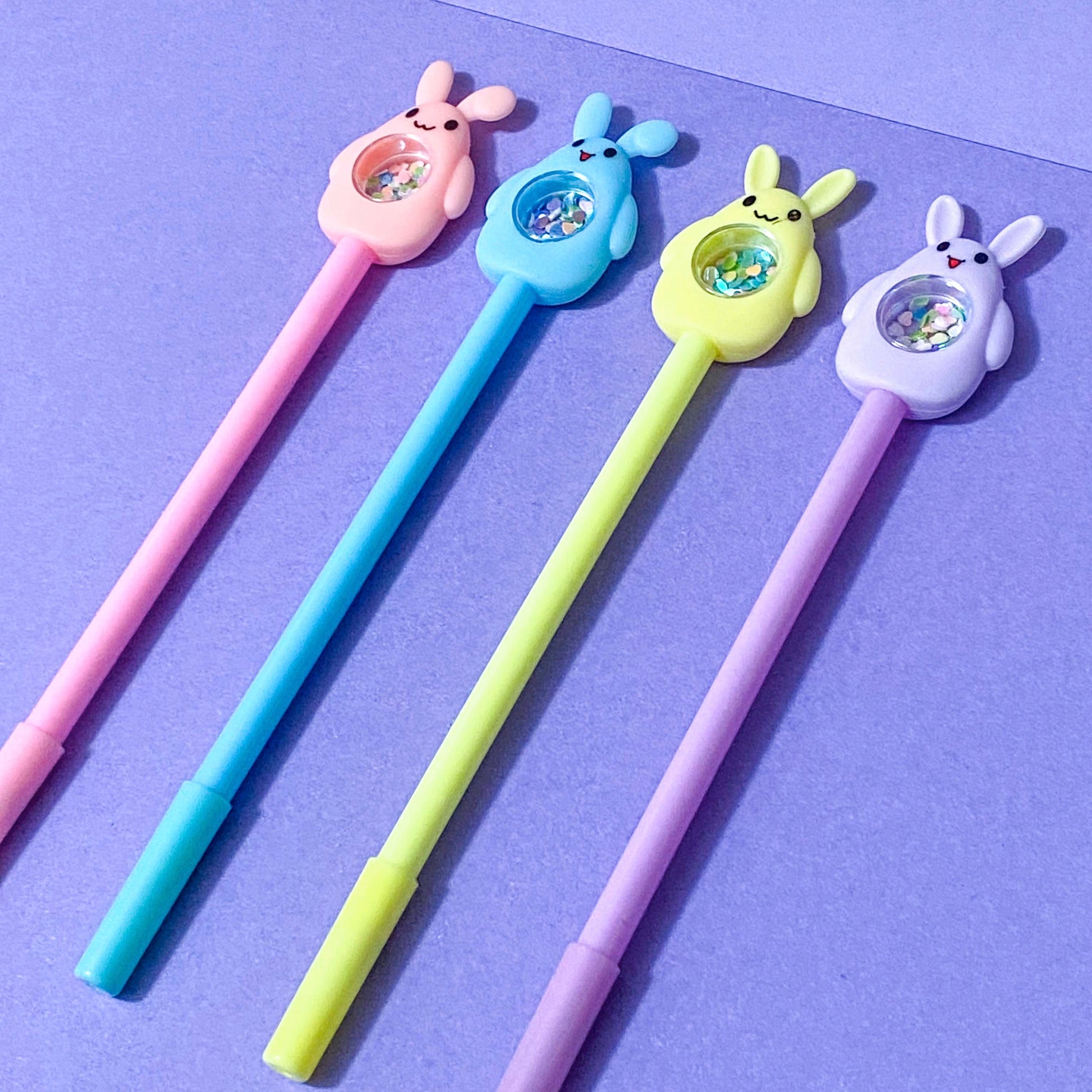 Four colourful black fine line pens with cartoon rabbit ends on a purple background