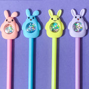Four colorful pens with rabbit-shaped ends with sequin shakers on a purple background