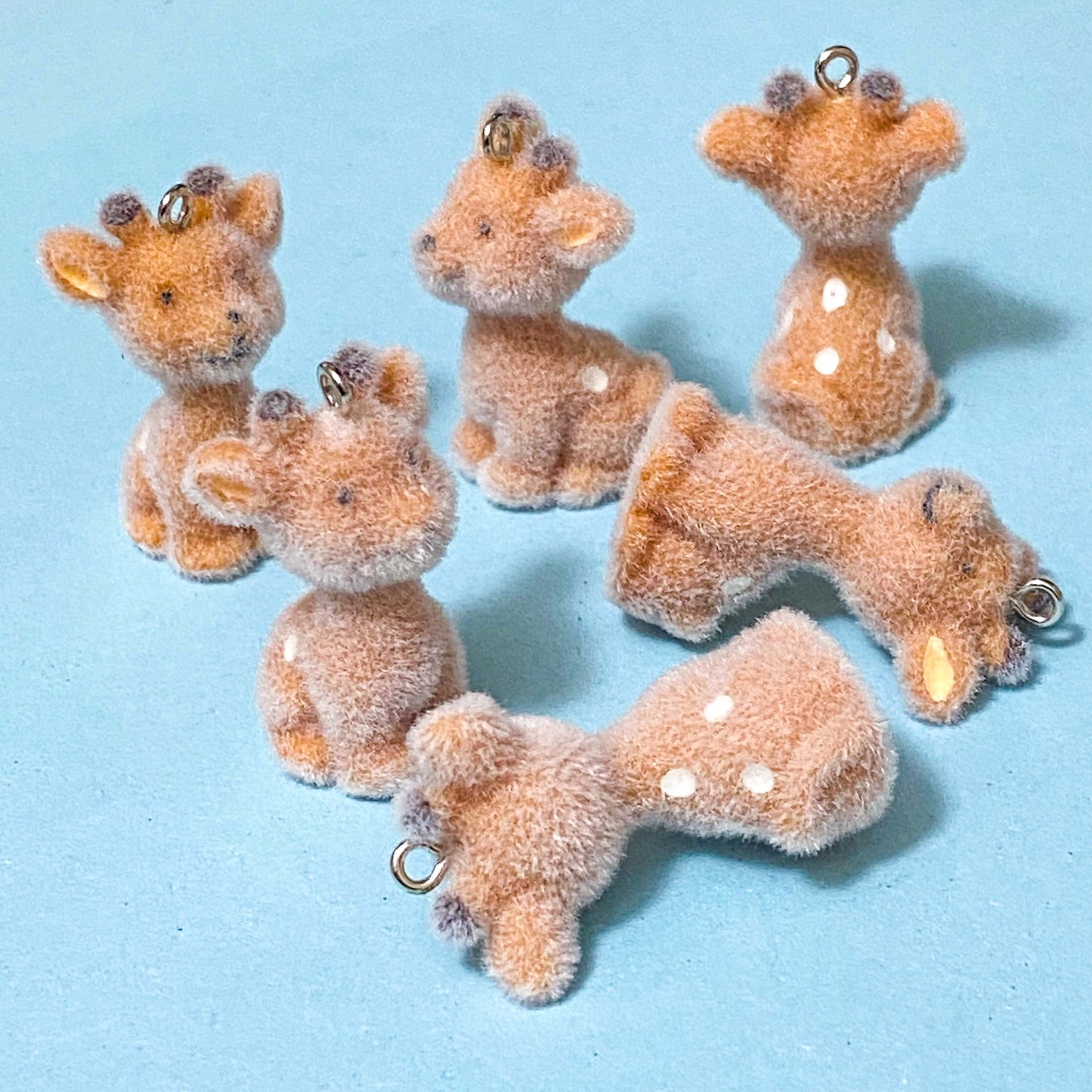 light brown baby deer flocked resin charms on a blue background