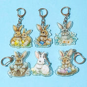 Set of rabbit-themed acrylic and silver metal keychains on a blue background