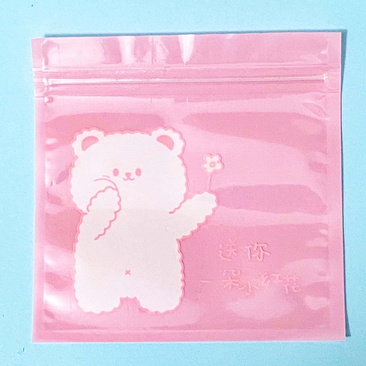 Pink ziplock plastic bag with a white bear design on a blue background