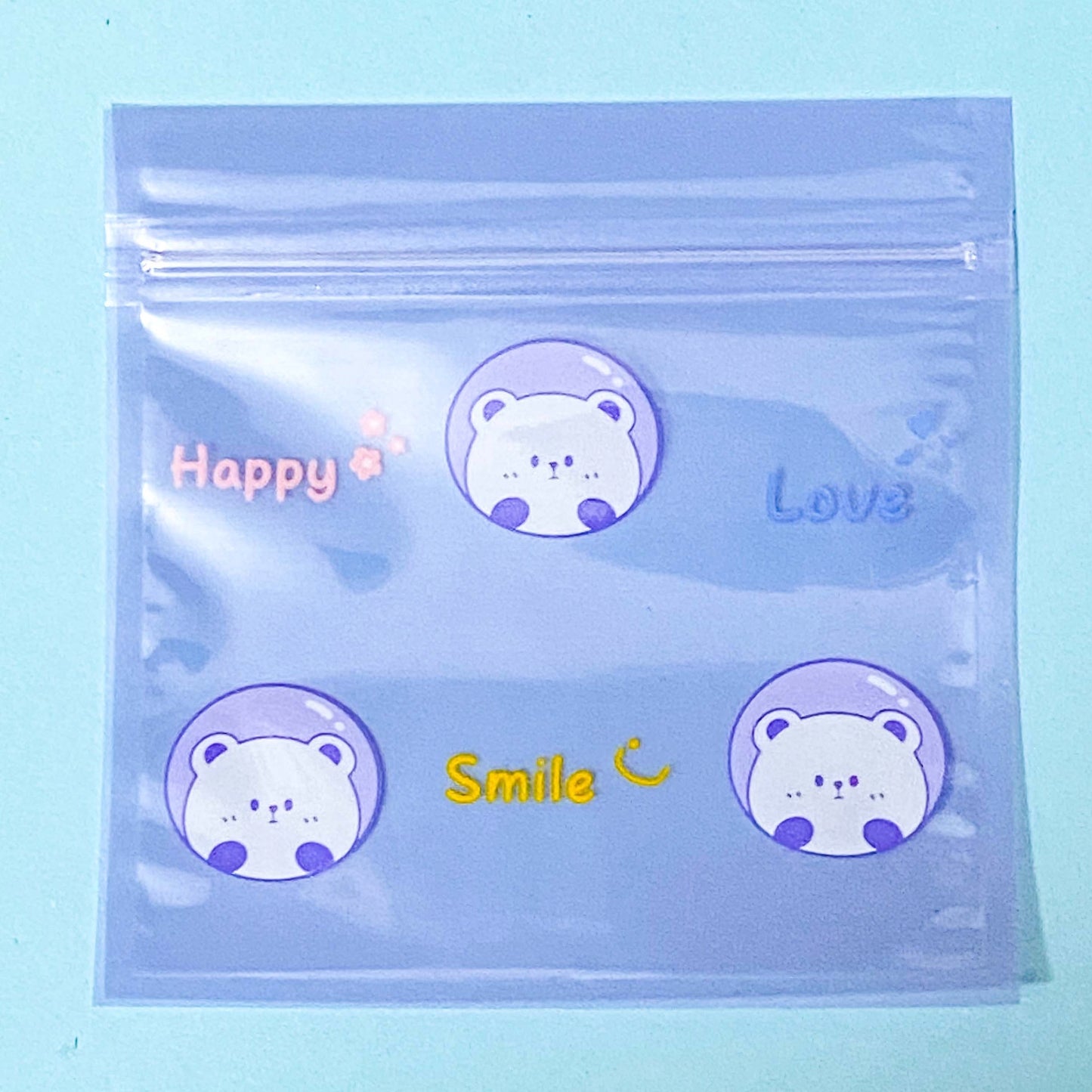 Clear plastic ziplock bag with bear-themed stickers labeled 'Happy', 'Love', and 'Smile' on a light blue background.
