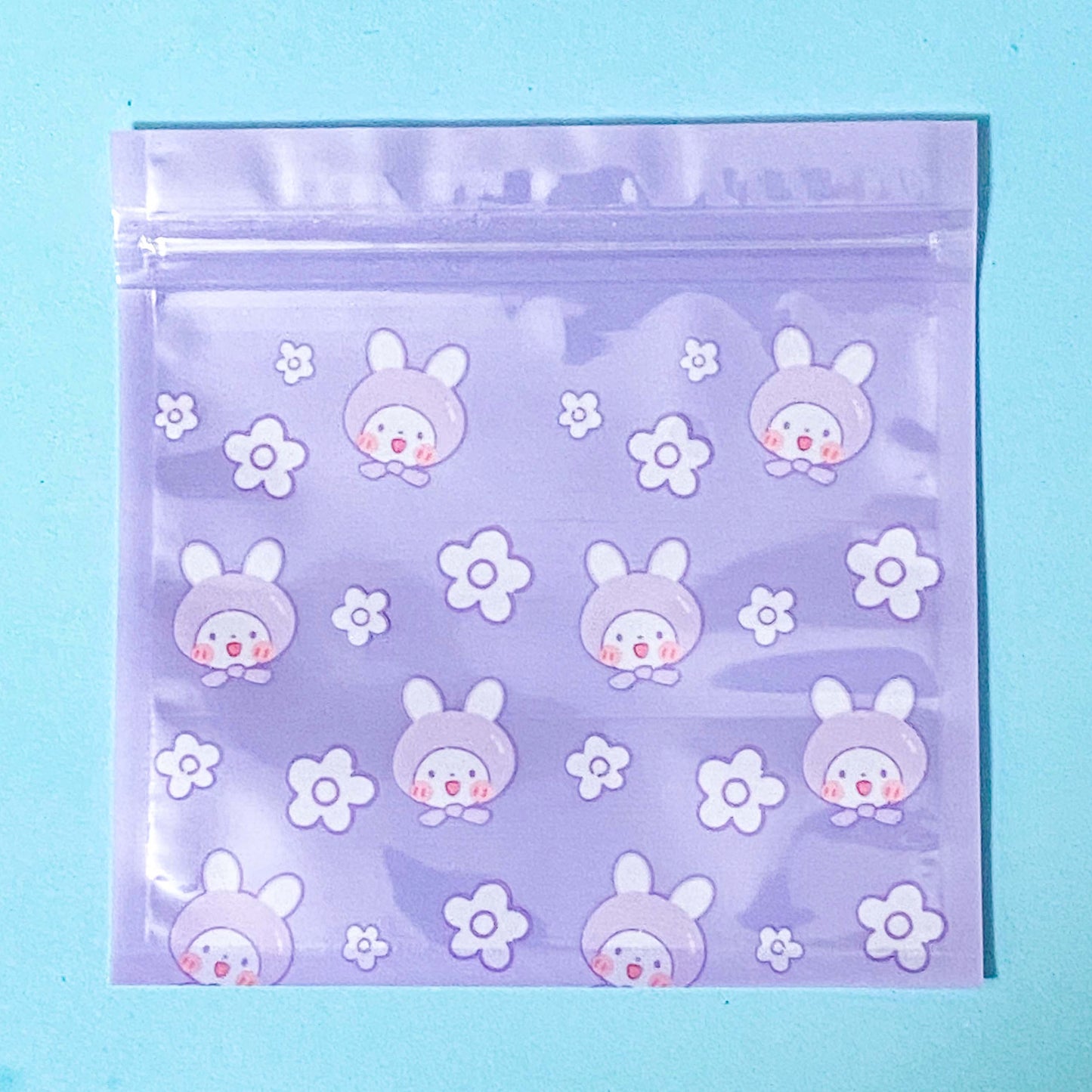 Clear plastic lilac re sealable ziplock bag with bunny and flower pattern on a blue background
