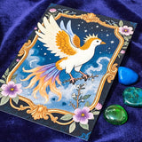 mythical phoenix art card on a blue background with come gemstones