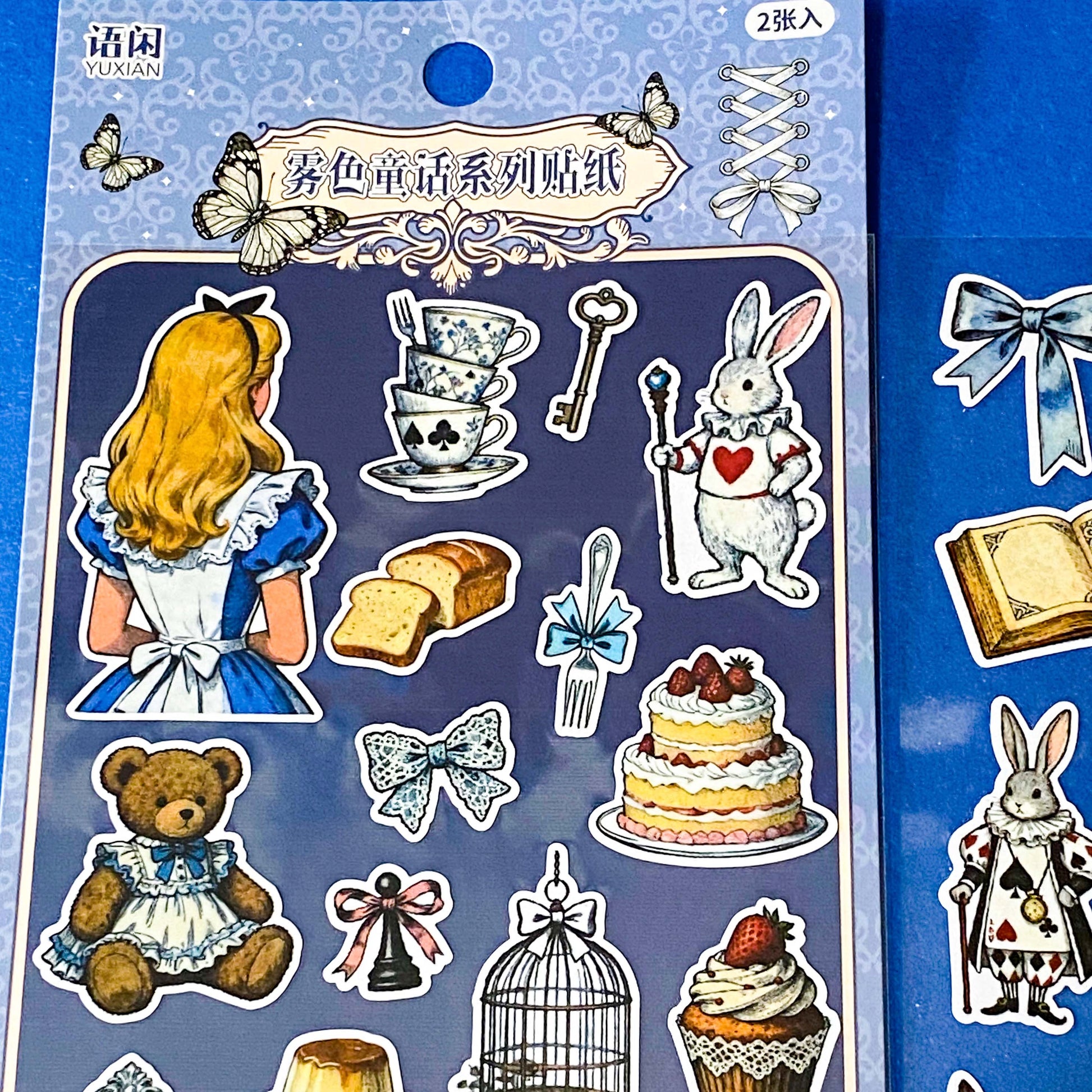 alice's adventures in wonderland matte sticker pack with two distinctive large clear decorative sheets featuring Alice, White rabbit, teacups, cakes, books, mushrooms and wonderland inspired illustrations. uk stationery shop.