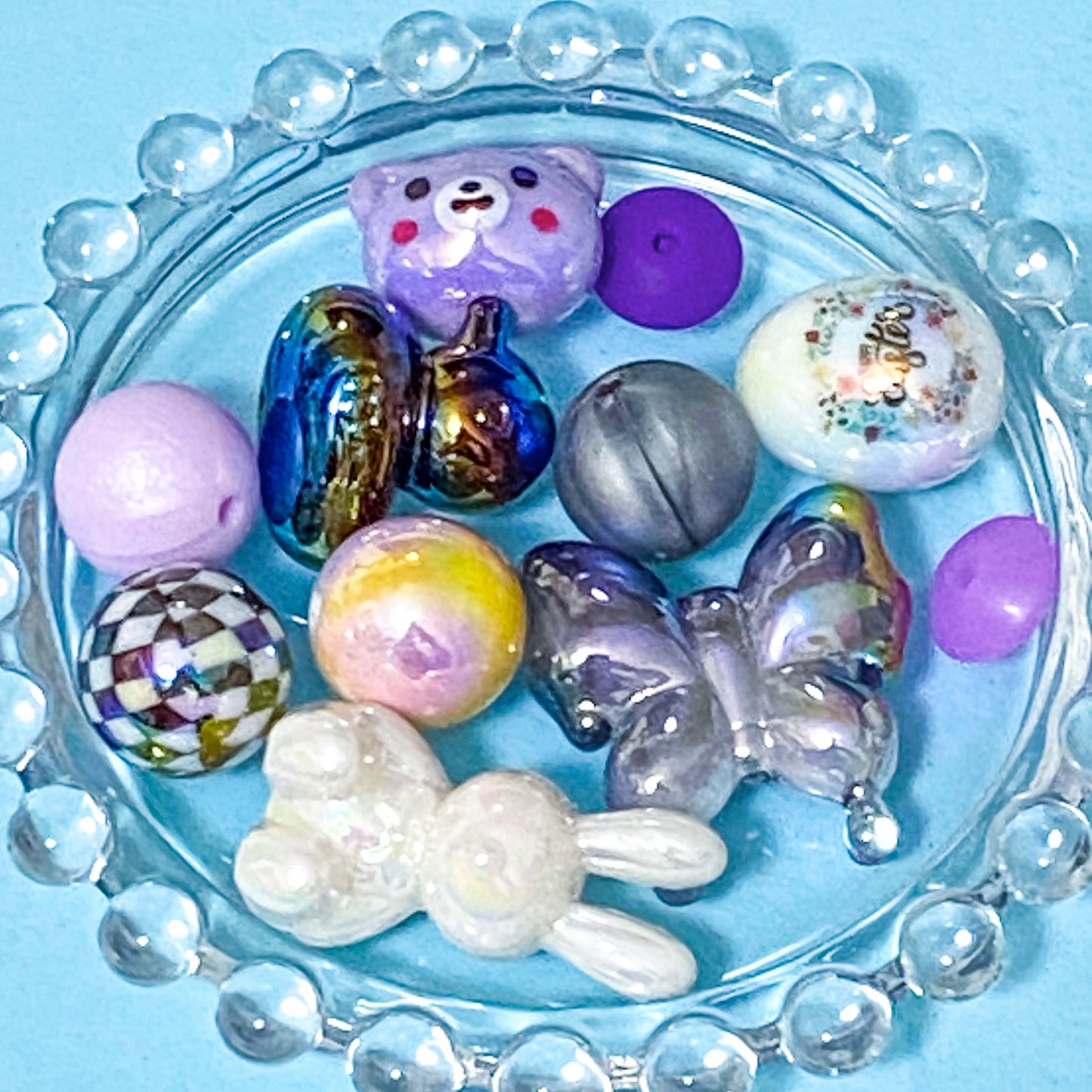 colour themed jumbo acrylic and silicone bead bundle in dark rainbow and lilac on blue background