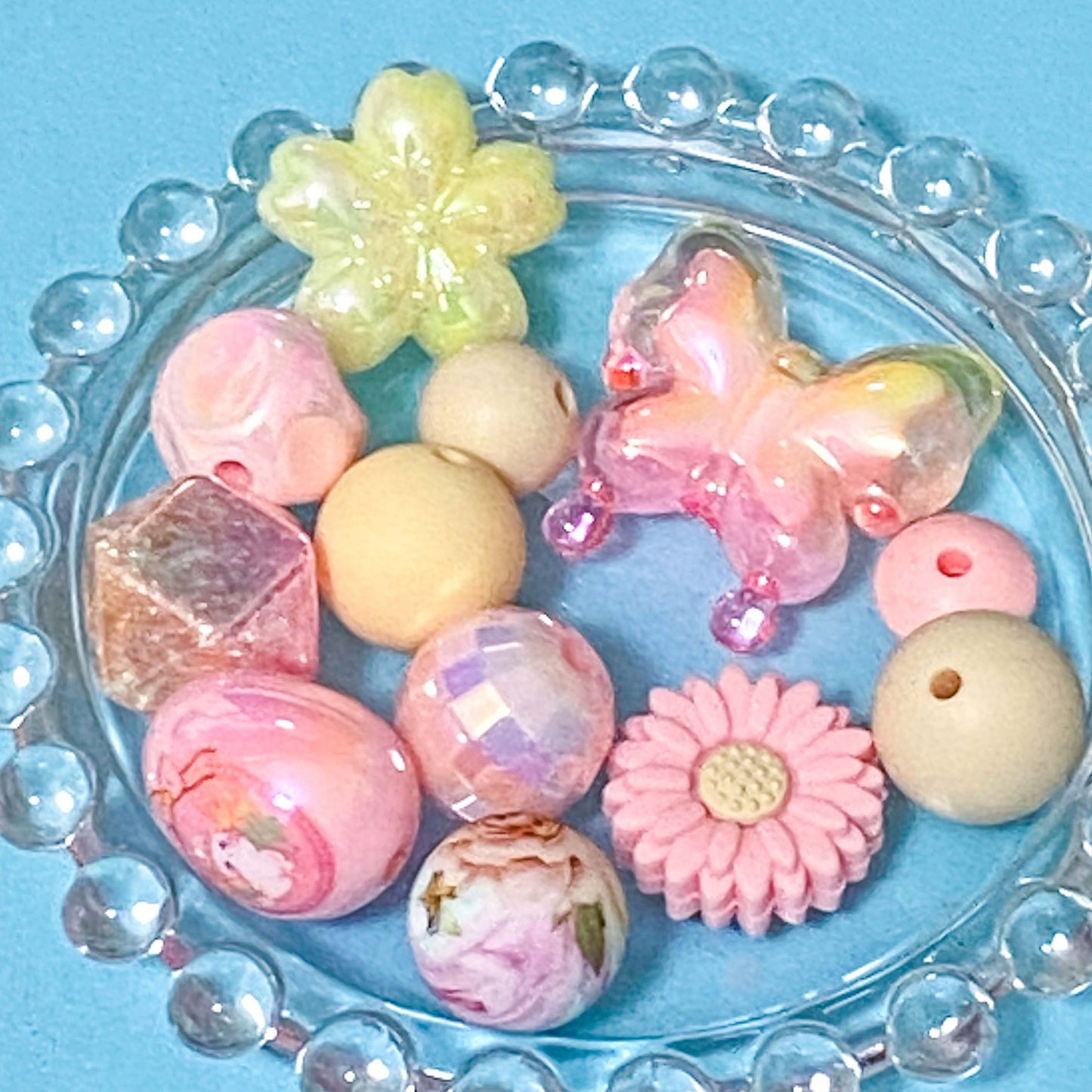 colour themed jumbo acrylic and silicone bead bundle in pink and pale yellow on a blue background