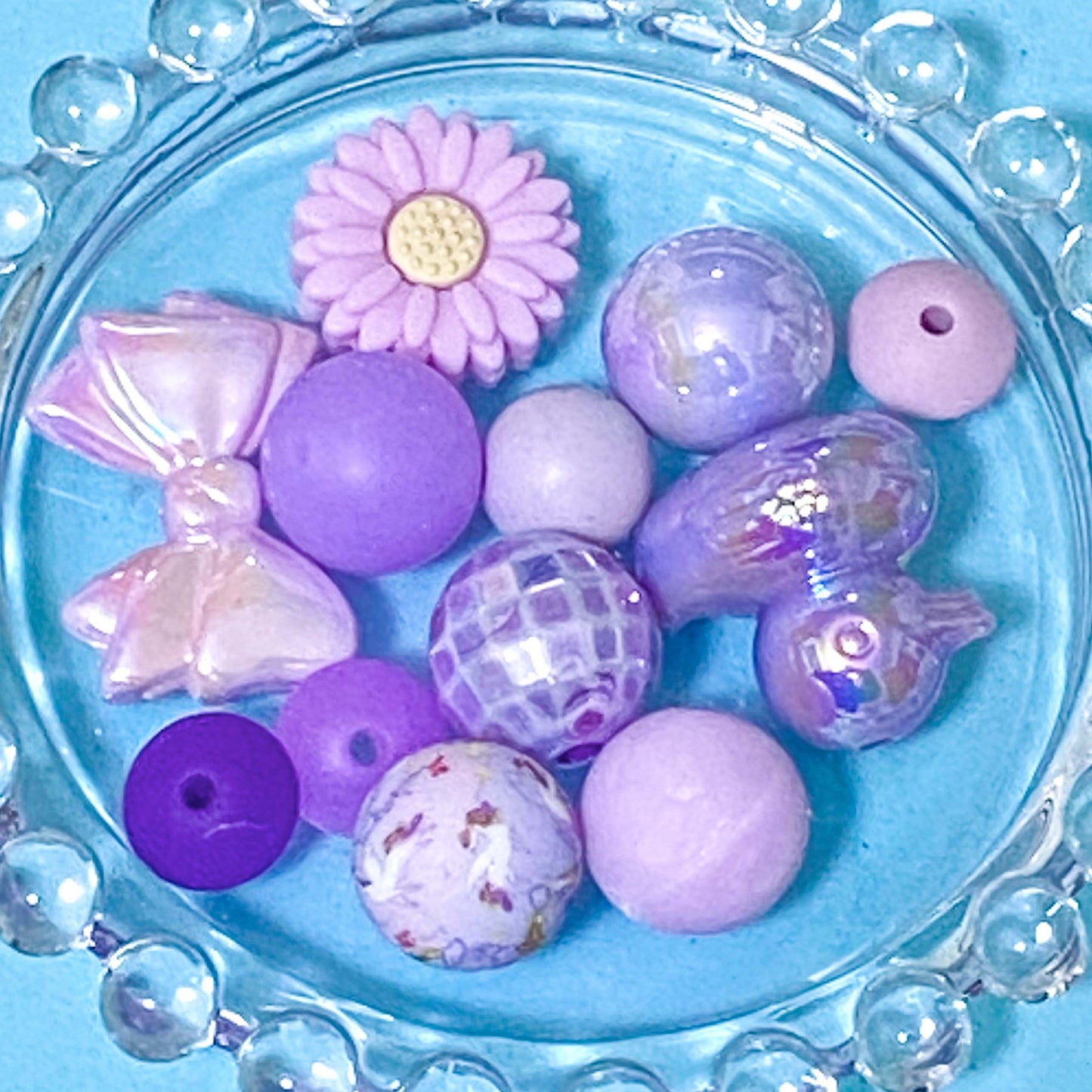 colour themed jumbo acrylic and silicone bead bundle in lilac and purple on a blue background