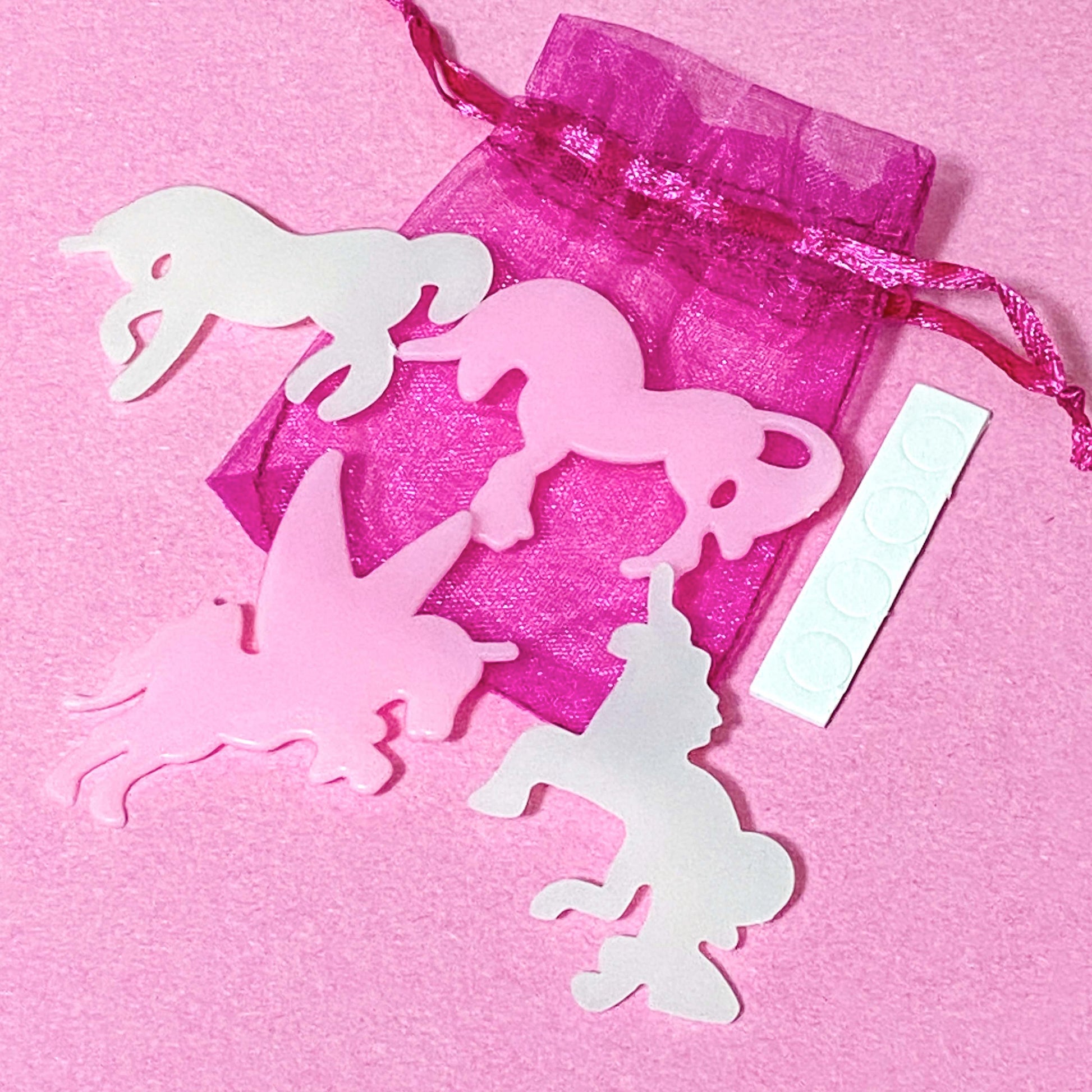 unicorn plastic glow in the dark shapes with stickers in a pink organza bag on a pink background