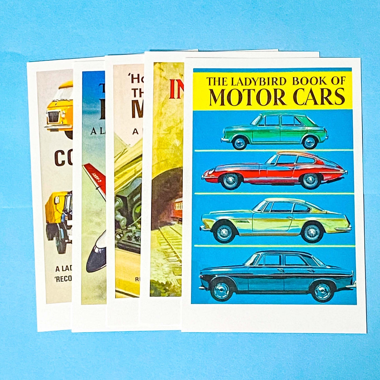 Collection of Ladybird book cover postcards about motor cars and transport on a blue background