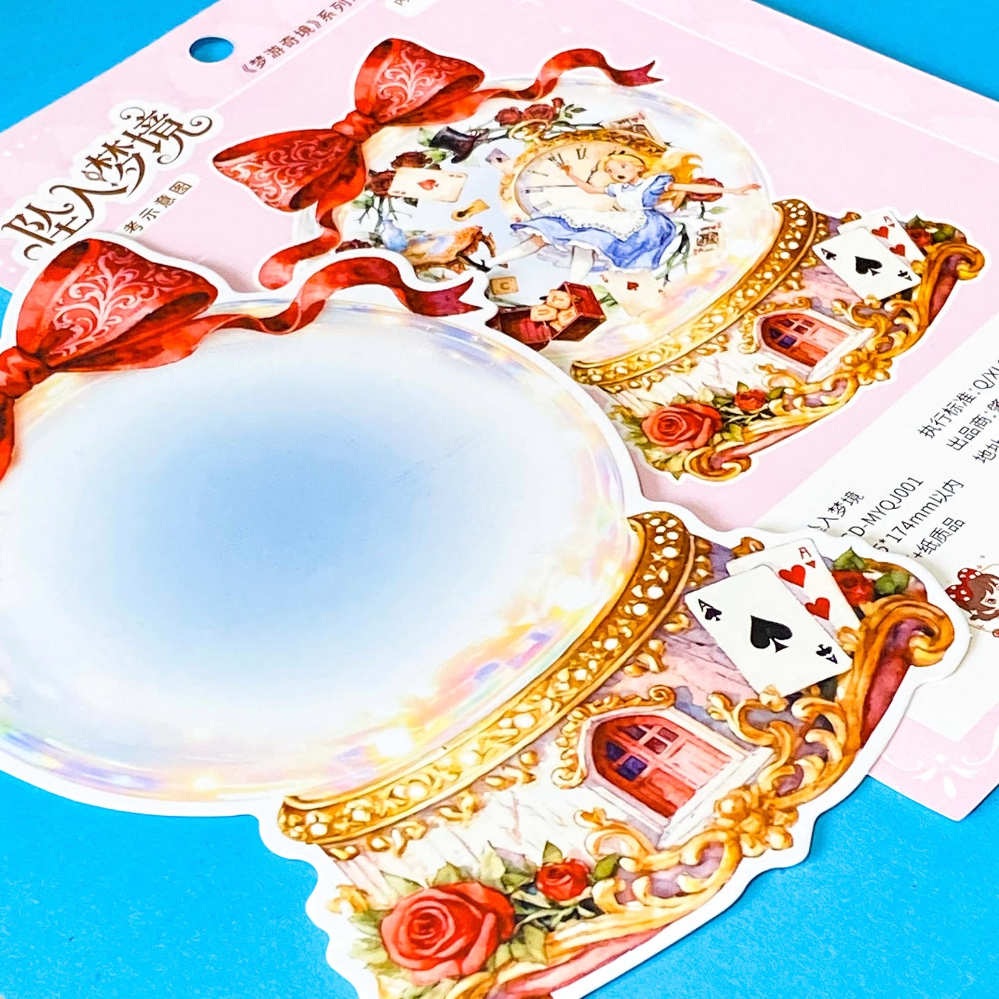large alice inspired falling into wonderland sticker set with oversized now globe scene card, transparent PET stickers, pocket watch, roses and playing cards details on pink backing card with bow