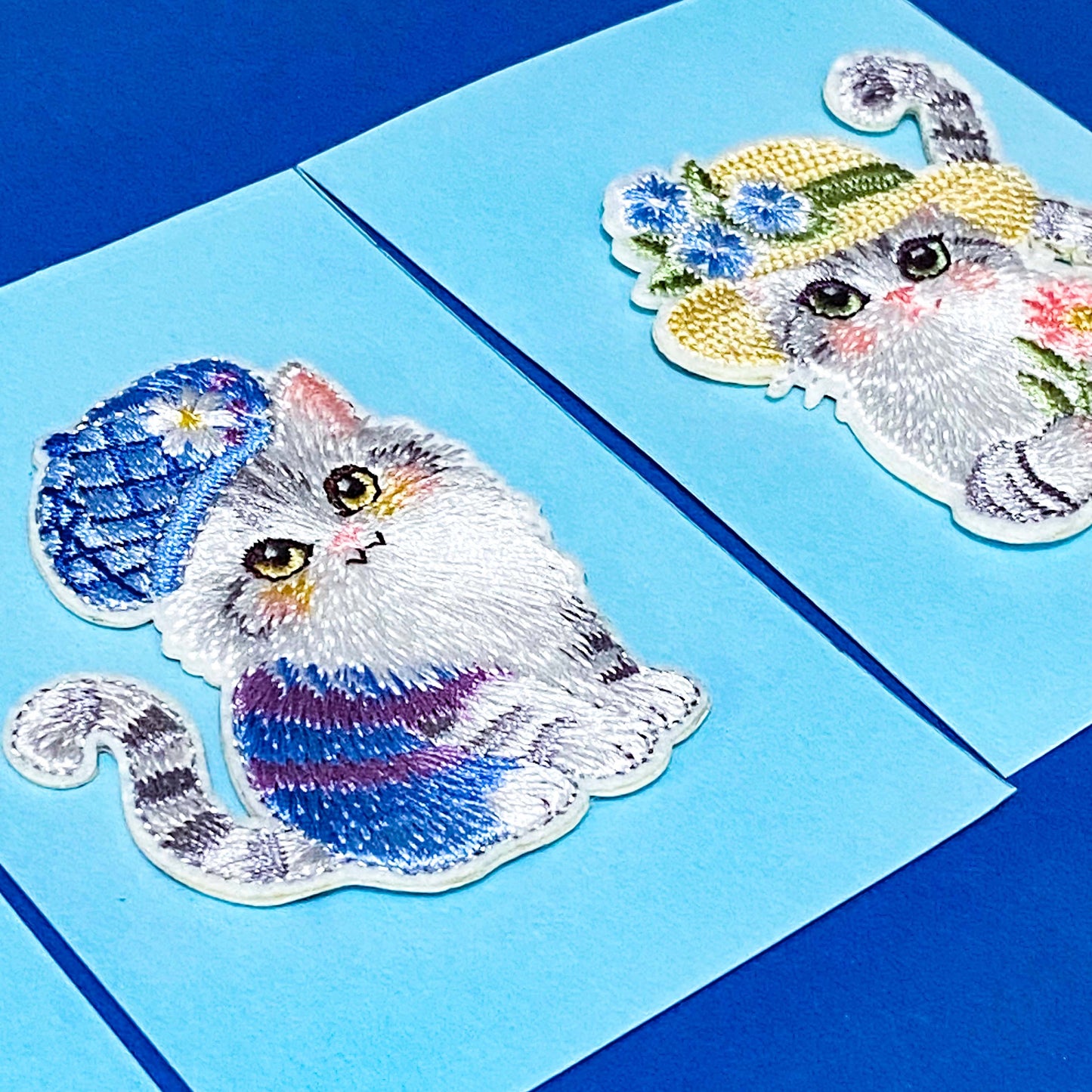 Embroidered cat patches with decorative hats on a blue background