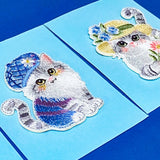 Embroidered cat patches with decorative hats on a blue background