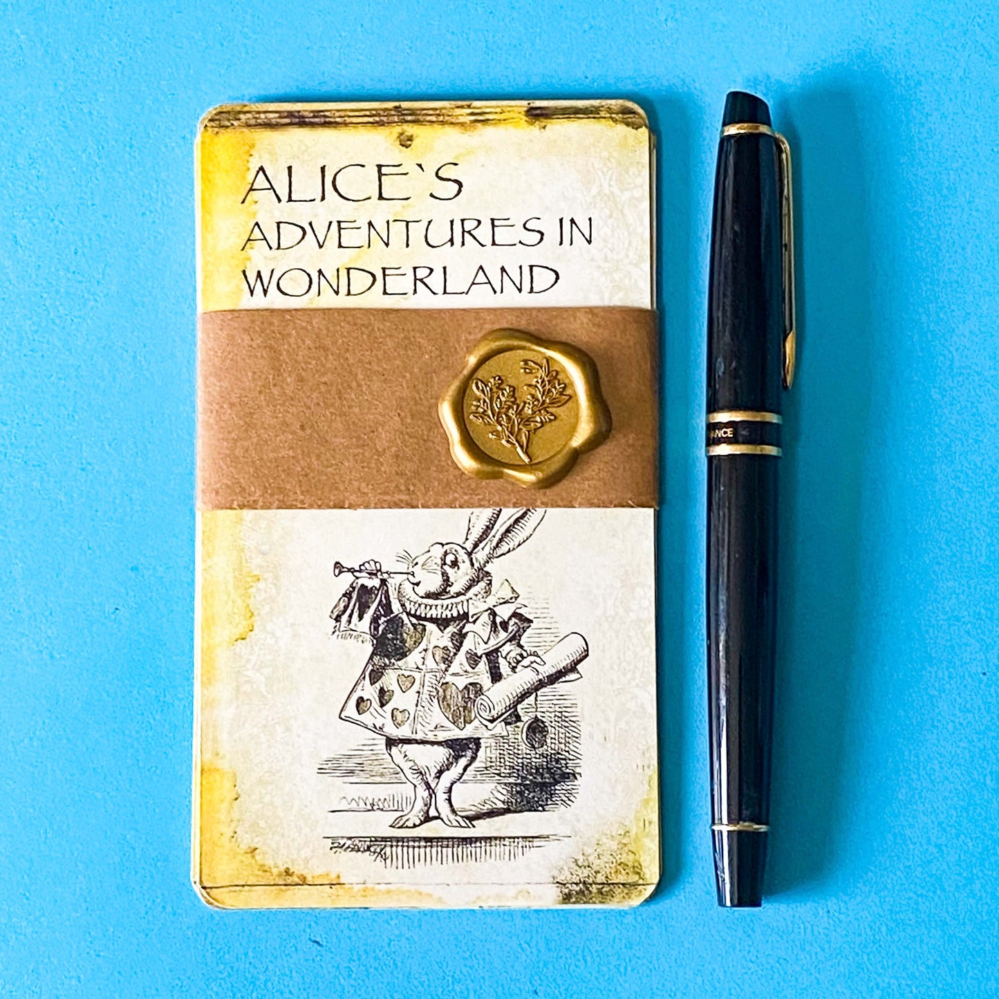 vintage alice in wonderland postcard set with aged sepia parchment illustrations, kraft belly band and wax seal presentation making a beautiful uk letterbox gift