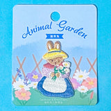 embroidered patch of a cute rabbit in a spring garden on a blue background