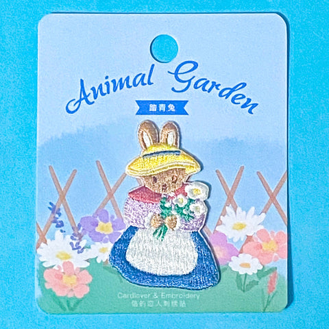 embroidered patch of a cute rabbit in a spring garden on a blue background
