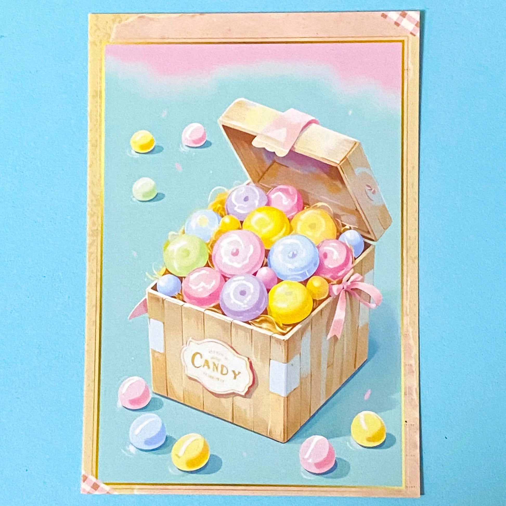 postcard showing a Wooden treasure chest filled with colourful candies and donuts on a blue background