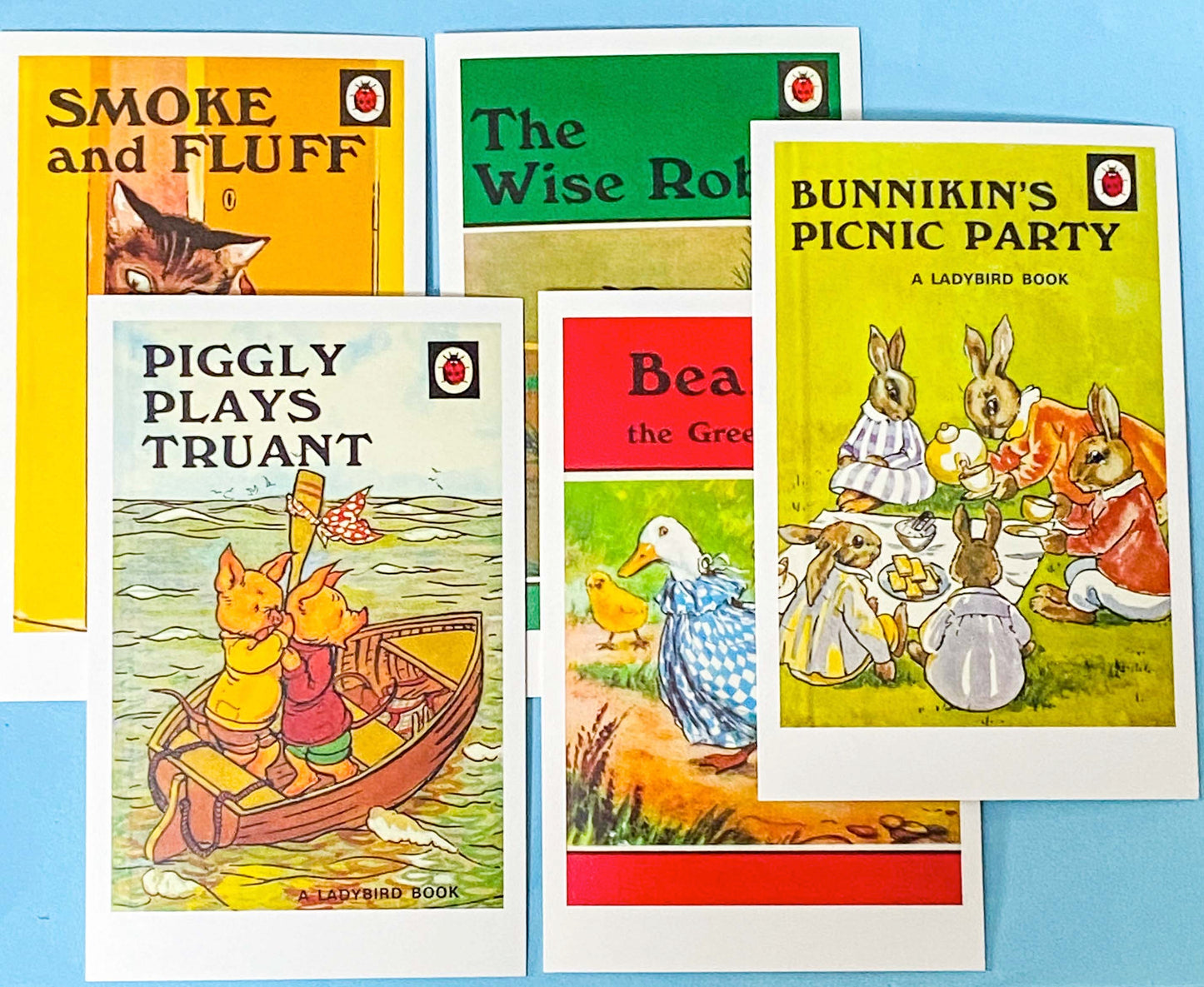 Collection of vintage Ladybird book cover postcards on a blue background with children's stories