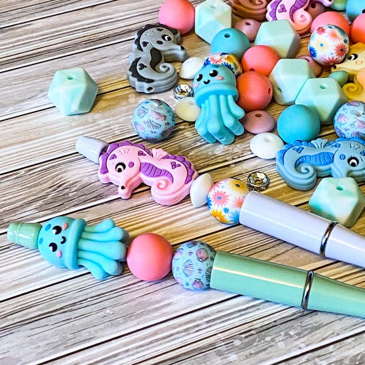ocean silicone beads set of 15 with seahorse and octopus focal beads and round and multi sided aqua, teal, turquoise, pink and blue beads to make a beaded pen