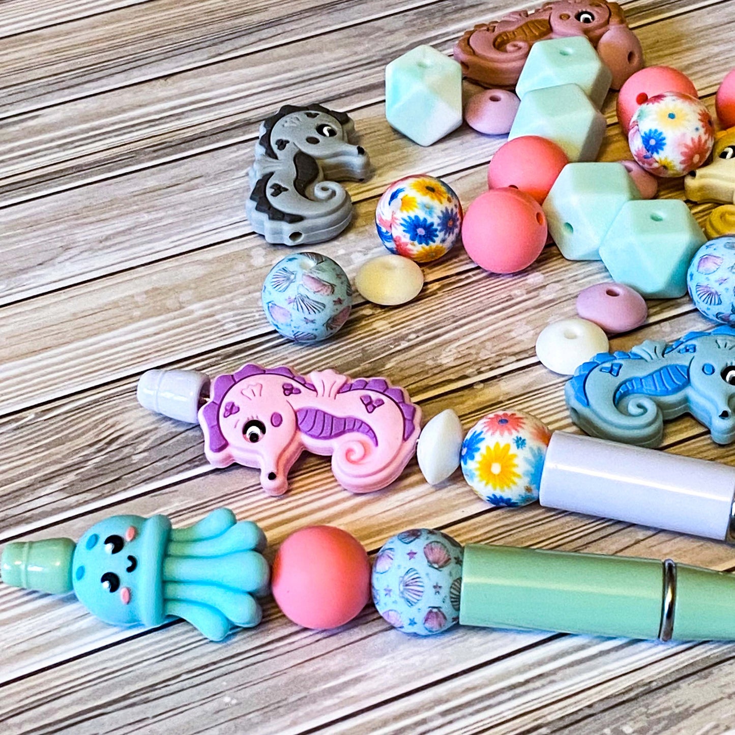 ocean silicone beads set of 15 with seahorse and octopus focal beads and round and multi sided aqua, teal, turquoise, pink and blue beads to make a beaded pen