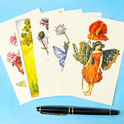 five vintage flower flairy postcards featuring poppy, scabious, knapweed, ragwort and red campion fairies on blue background