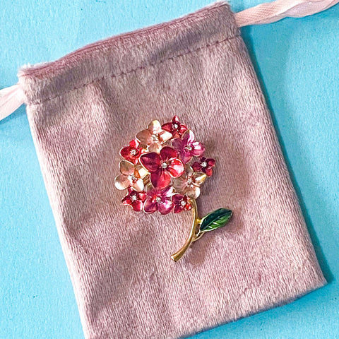 Floral hydrangea brooch on a pink velvet bag against a blue background