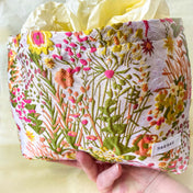wildflower meadow tapestry pouch with colourful woven floral design including daisies, cream lining, concealed zip closure and gusseted base. Cream, orange, lemon, soft green and white design. Subtle sheen. Large cosmetic bag or toiletry pouch. Uk botanical gift shop.