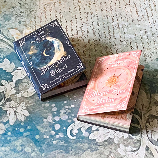 two miniature vintage style scrapbooking vellum and paper books, interstellar object and magic star array, with celestial themed covers