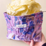 Elegant satin-finish tapestry pouch featuring woven lavender and blue florals with gold metallic thread, cream lining, concealed zip and gusseted base. Ideal for cosmetics and stationery