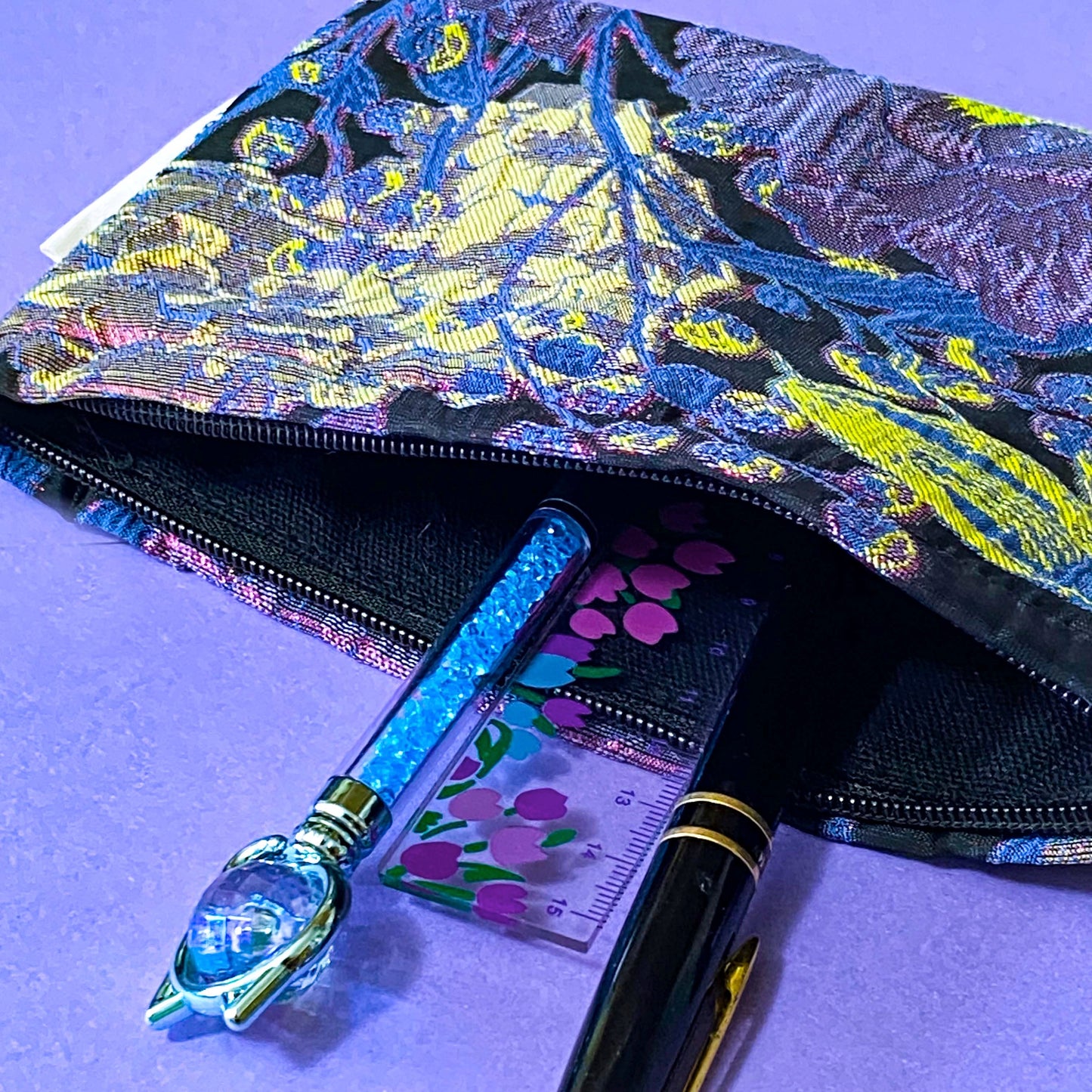 sapphire and magenta twilight luxury woven tapestry cosmetic or jewellery pouch with a sapphire blue botanical leaves and vibrant cerise florals. fully lined in black fabric and finished with a concealed zip.