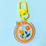 Decorative acrylic keychain with orange sunflowers and 'Happy Life' text on a light blue background