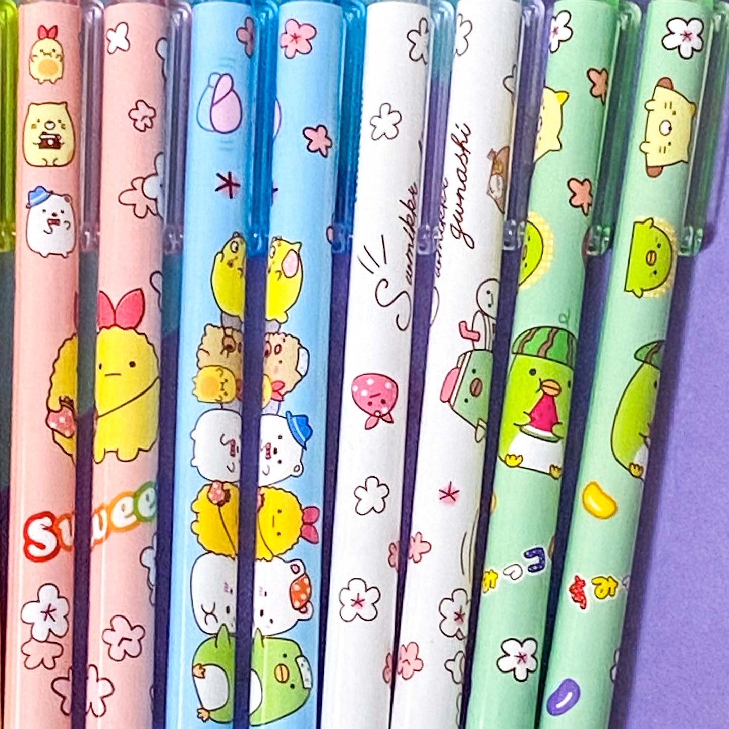 Set of colorful pens with cartoon character designs on a purple background