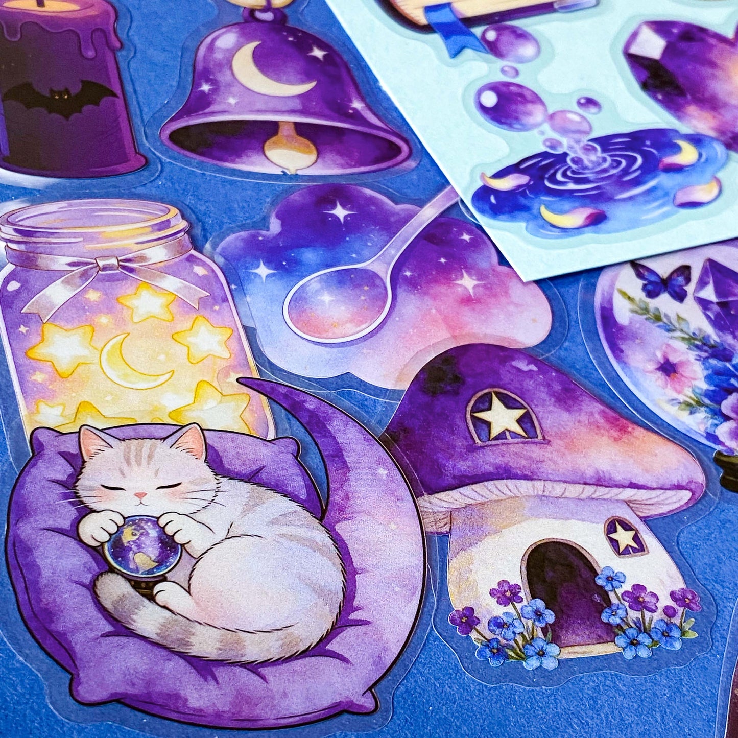 pack of 50 magical fantasy stickers featuring crystal balls, spell books, moonlit scrolls, enchanted mushrooms, ravens, potion bottles, celestial moons, magical animals and crystal gardens in lavender, violet and blue tones. UK stationery shop and letterbox gifts store.