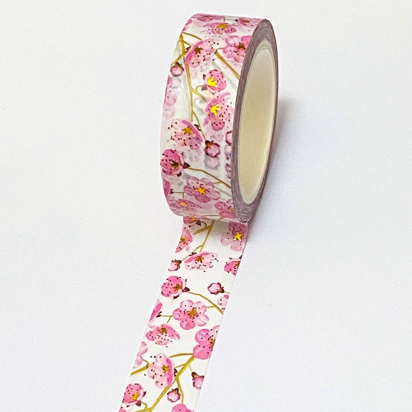 Roll of floral washi tape with pink flowers and gold foil highlights on a white background