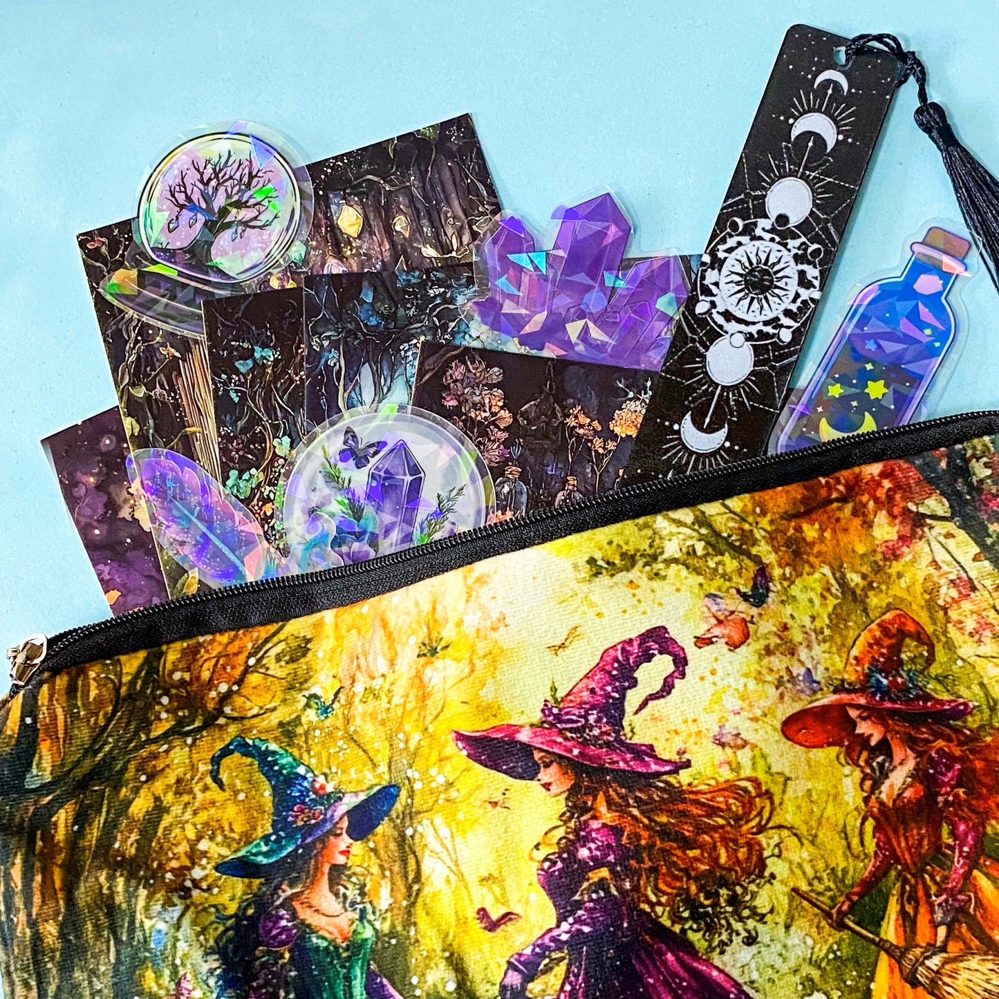 witchy stationery bundle with colourful witch pouch, forest magic postcards, holographic stickers and moon phase bookmark with tassel on a blue background