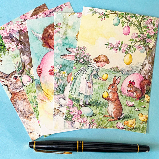 vintage storybook postcard set of 5 featuring a girl with rabbits and pastel eggs in a spring garden on a blue background