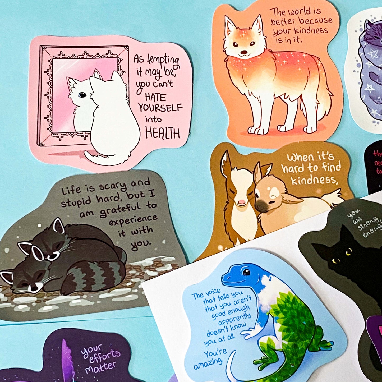 colourful glossy affirmation stickers with cute animals and positive mental health messages including cats, raccoons, lizard, fox and black cat on pastel background