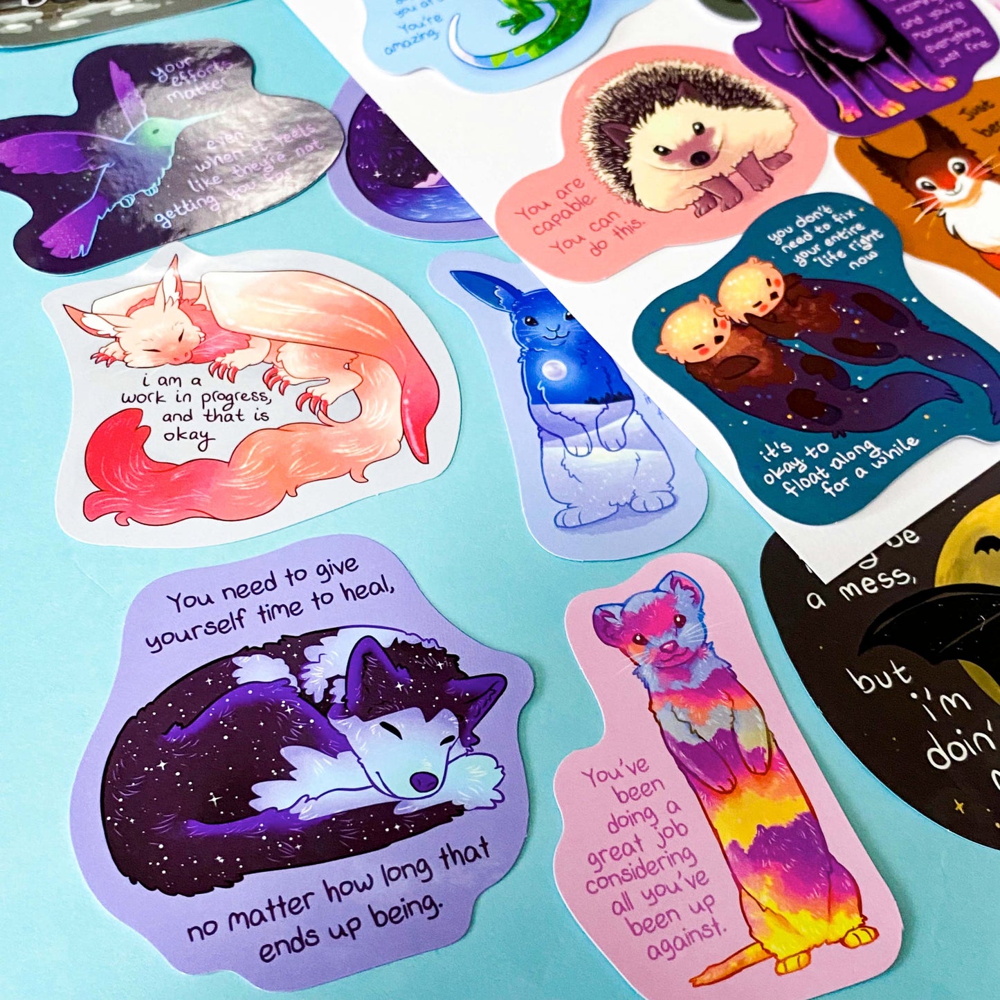 colourful glossy affirmation stickers with cute animals and positive mental health messages including foxes, cats and fantasy creatures on pastel background