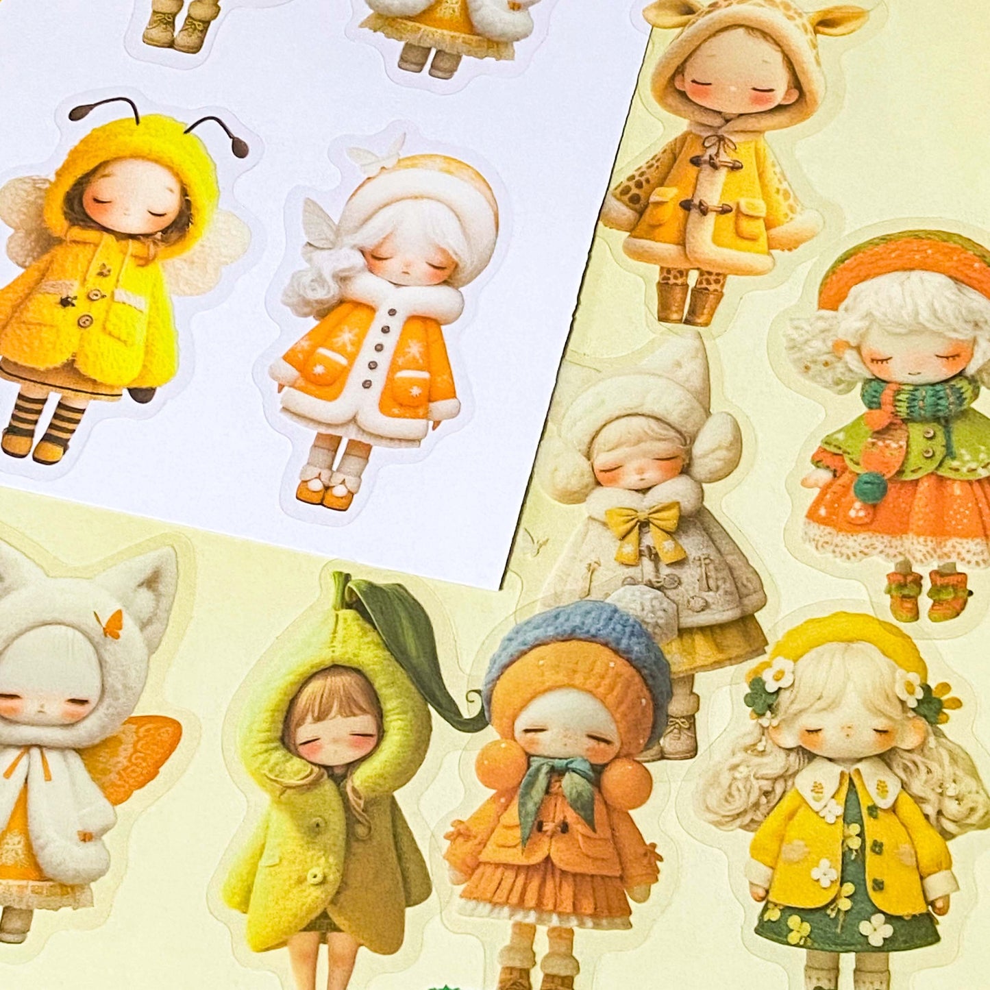 sunshine yellow and orange sticker set with 20 large PET doll stickers of girls in cute outfits and costumes, including a pea, cat, bee and giraffe. Adorable designs of cosy winter clothing and animals. 
