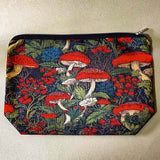 deep red canvas mushroom zip pouch featuring red toadstools, berries and botanical foliage on a dark forest background. Uk gift shop for letterbox gifts.