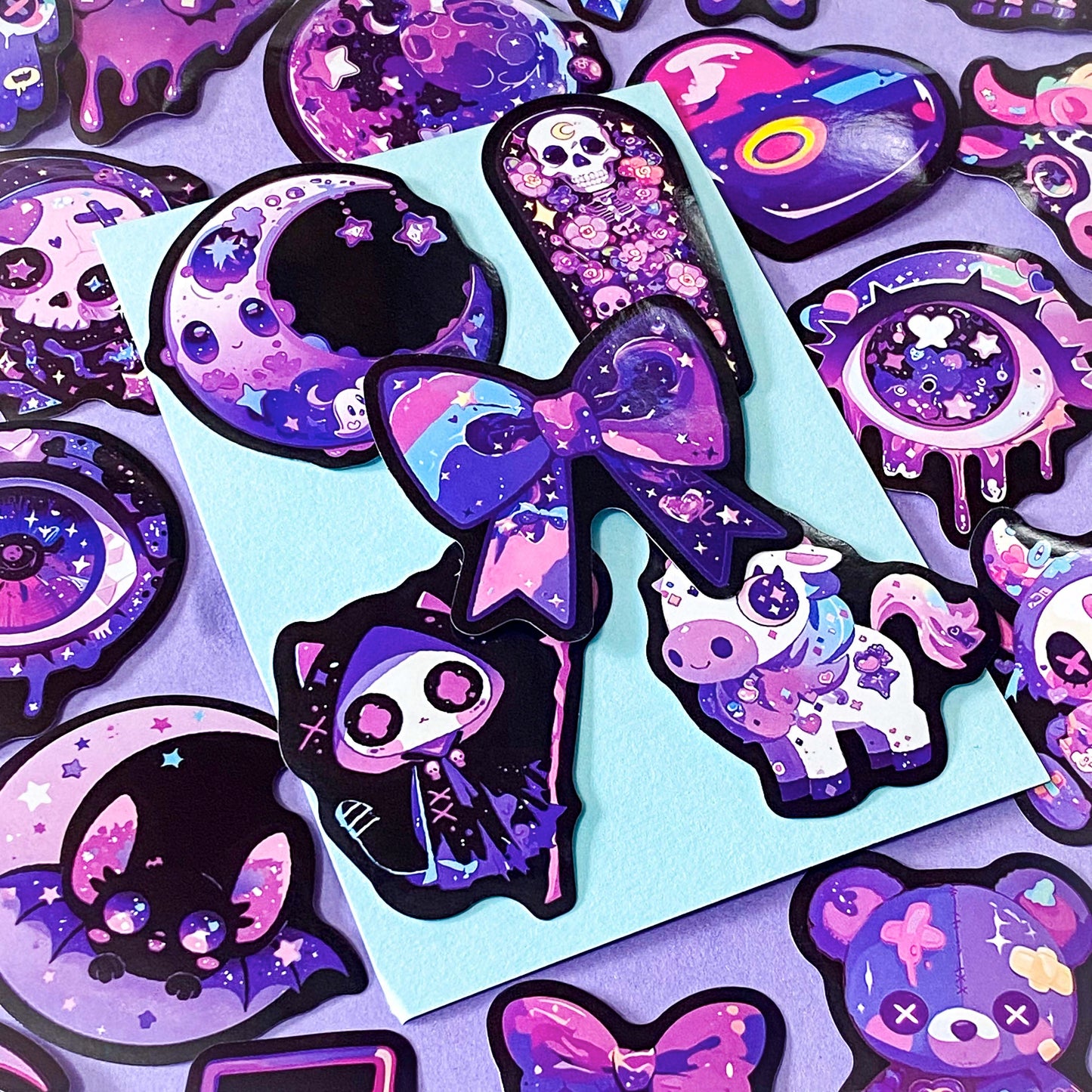 pack of 50 large glossy laptop stickers featuring bats, skulls, moons, owls, eyes, cows, unicorns, potion bottles, crystals, celestial artwork in purple, pink , lilac and blue tones. vibrant pack. uk cute stickers shop.