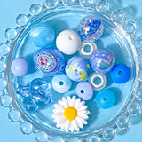 Assorted blue and white beads with a daisy on a blue background