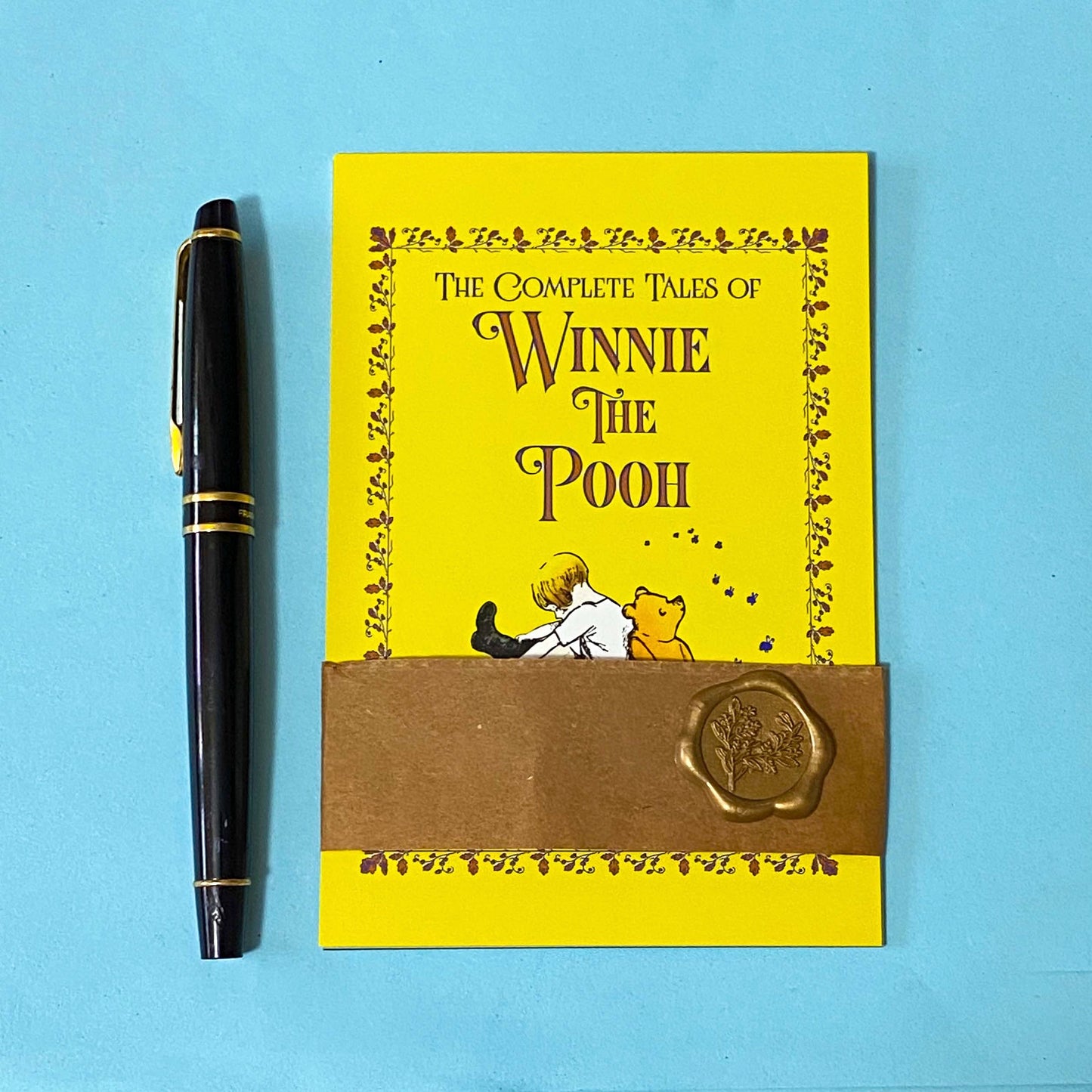 set of 3 vintage storybook cover postcards including winnie the pooh, moby dick and wind in the willows wrapped in a kraft belly band with wax seal sticker