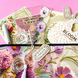 vintage floral letterbox gift set with large flower pouch, pearly white metal pen, daisy tassel acrylic bookmark, floral postcards and vintage decorative journaling stickers on pink background. UK cute gifts and stationery sets.