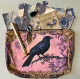 gothic raven themed letterbox gift set with ornate crow fabric pouch, gold metal pen, enamel raven pin brooch, vintage metal bookmark, dark paper stickers and scrapbook papers. Uk gift shop with mystical and witchy gifts.