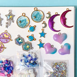 Assorted colorful jewelry charms and beads with a celestial theme on a white tray with a blue background