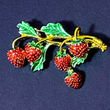 Strawberry brooch with green leaves on a dark blue background