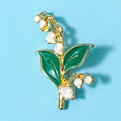 lily of the valley Brooch with green leaves and white flowers on a blue background